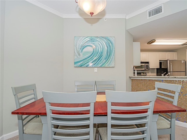 carpeted dining room with ornamental molding