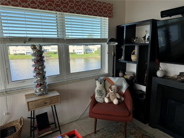 sitting room with light tile patterned floors, a water view, and plenty of natural light