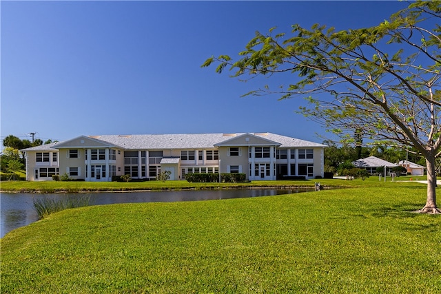 rear view of property with a lawn and a water view