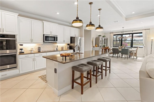 kitchen featuring white cabinetry, appliances with stainless steel finishes, a kitchen island with sink, and light tile patterned floors