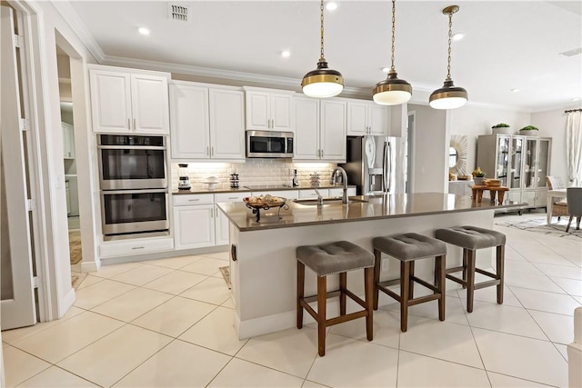 kitchen with sink, crown molding, stainless steel appliances, white cabinets, and a center island with sink