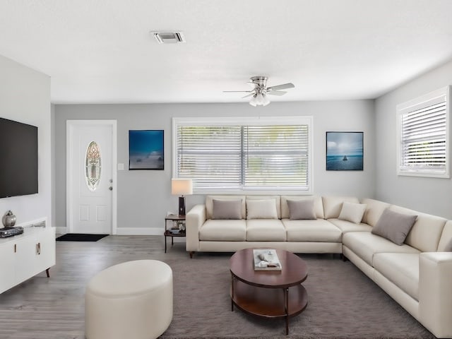 living room with plenty of natural light, dark wood-type flooring, and ceiling fan