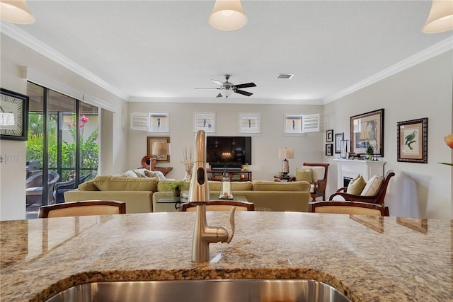 kitchen featuring plenty of natural light, sink, light stone counters, and crown molding