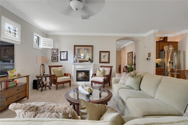 carpeted living room with crown molding and ceiling fan