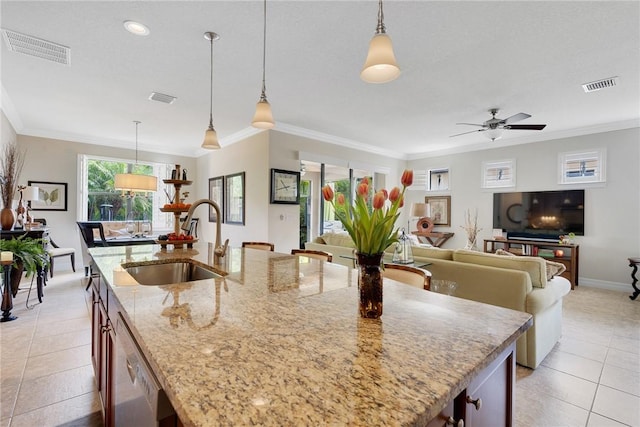 kitchen with pendant lighting, light stone countertops, sink, and a kitchen island with sink