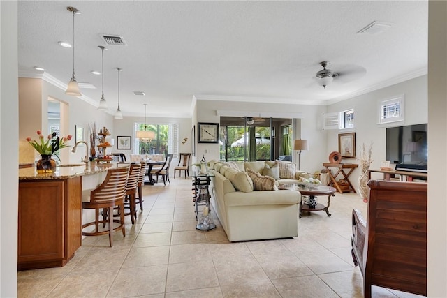 living room with light tile patterned floors, ceiling fan, crown molding, and sink