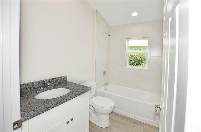 full bathroom featuring tiled shower / bath combo, vanity, hardwood / wood-style floors, and toilet