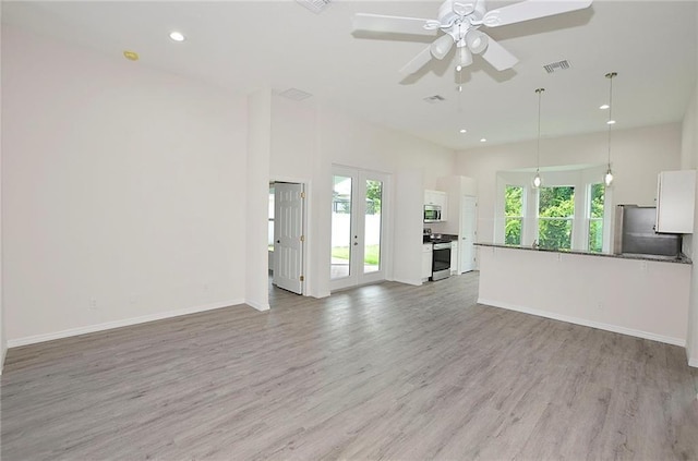 unfurnished living room featuring french doors, ceiling fan, a healthy amount of sunlight, and light hardwood / wood-style floors