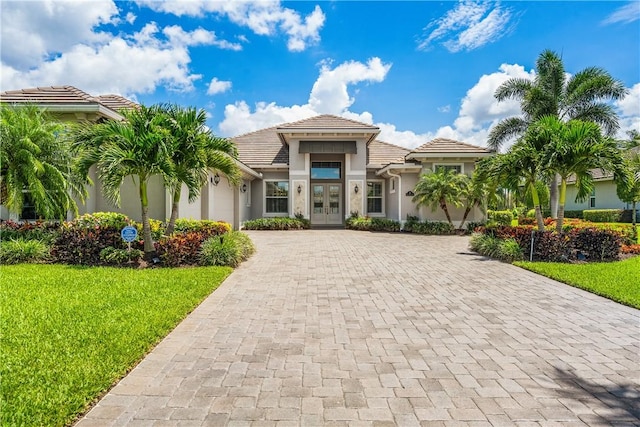 mediterranean / spanish house featuring a front lawn and french doors