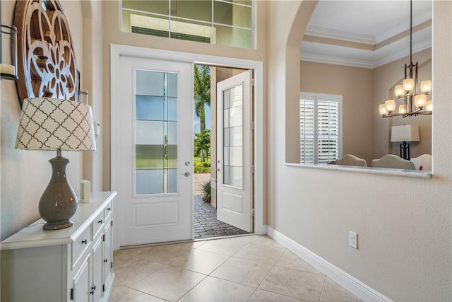 doorway featuring ornamental molding, a tray ceiling, and light tile patterned floors