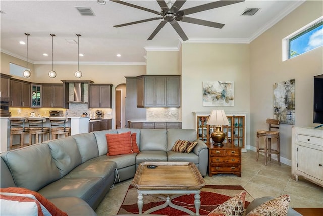 living room with crown molding, light tile patterned floors, and ceiling fan