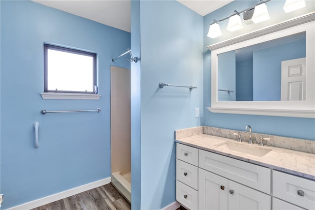 bathroom featuring walk in shower, vanity, and wood-type flooring