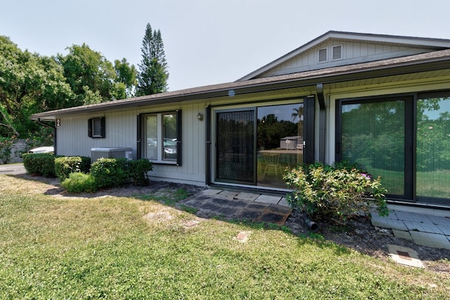 rear view of property with a lawn and cooling unit