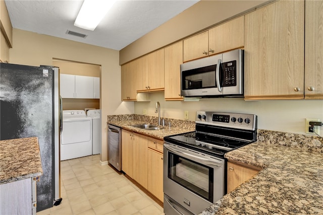 kitchen with light brown cabinets, stainless steel appliances, sink, and washer and dryer