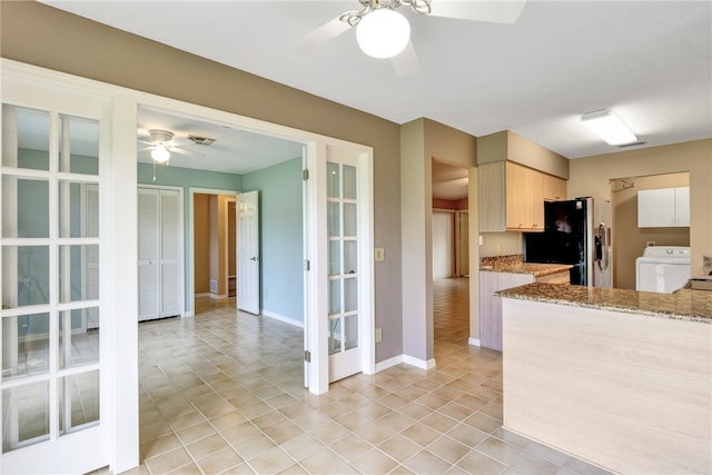 kitchen with black fridge, light stone counters, washer / dryer, light brown cabinetry, and ceiling fan