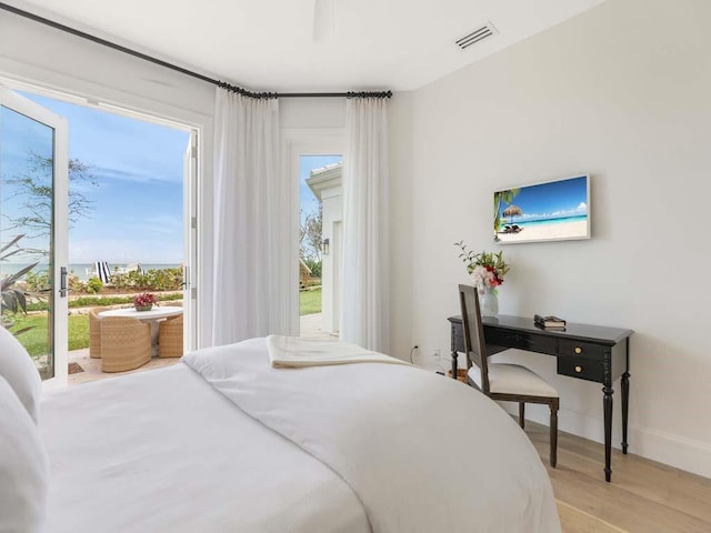 bedroom featuring multiple windows, access to exterior, and light hardwood / wood-style flooring