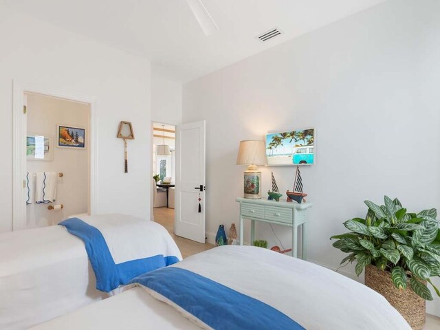 bedroom featuring lofted ceiling with beams, a barn door, and light hardwood / wood-style floors