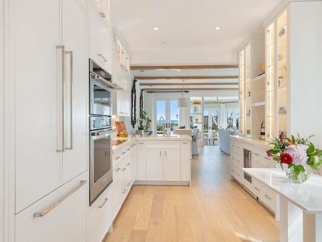 kitchen with white cabinetry, oven, light hardwood / wood-style floors, kitchen peninsula, and paneled refrigerator