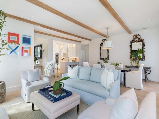 living room featuring beamed ceiling and light hardwood / wood-style floors