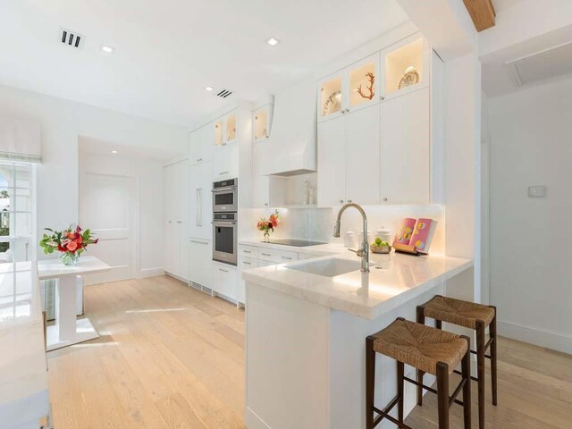 dining space with beamed ceiling, a fireplace, sink, and light wood-type flooring