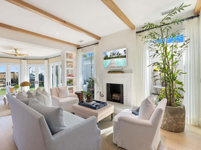 living room with a brick fireplace, light wood-type flooring, beam ceiling, and french doors