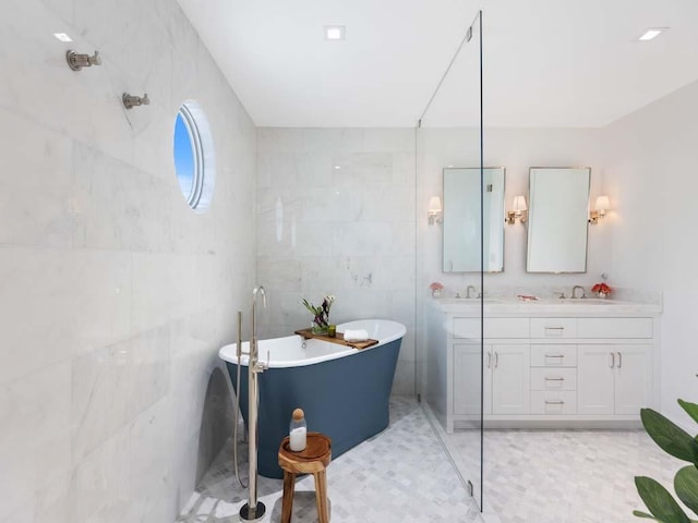 bathroom with vanity, tile walls, and a tub