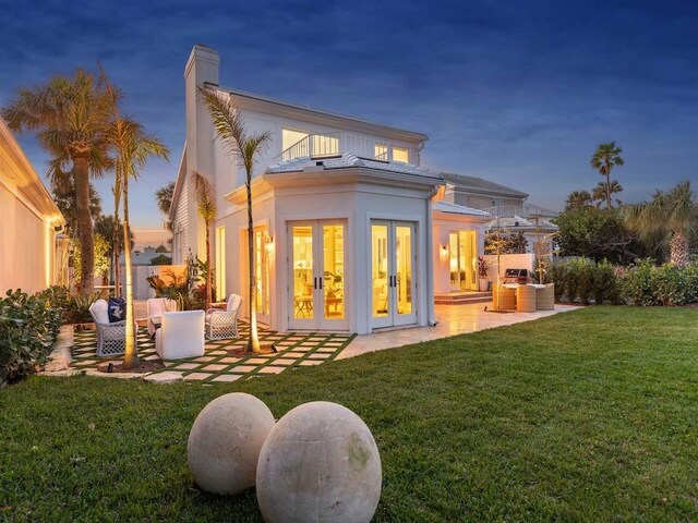 rear view of house featuring french doors, a sunroom, a yard, and a patio area