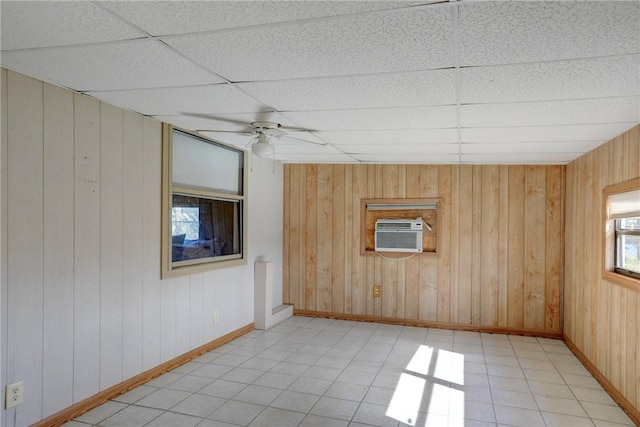 unfurnished room with a drop ceiling, light tile patterned floors, an AC wall unit, and ceiling fan