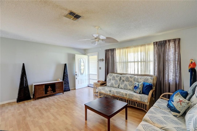 living room with ceiling fan, light hardwood / wood-style floors, and a textured ceiling