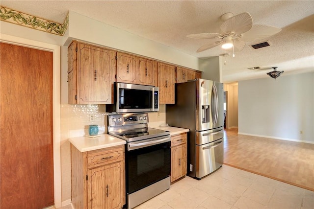 kitchen featuring ceiling fan, backsplash, stainless steel appliances, and a textured ceiling