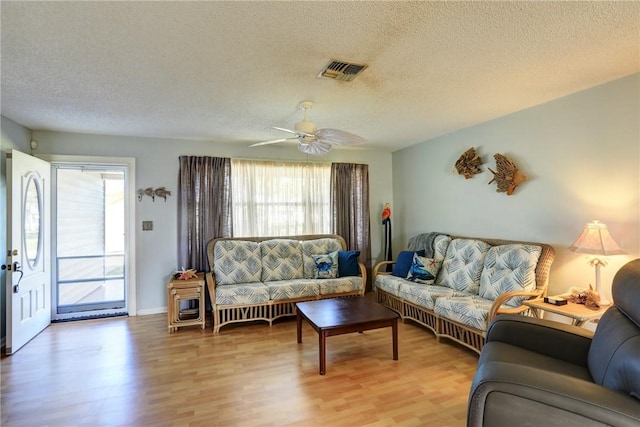 living room with hardwood / wood-style flooring, ceiling fan, and a textured ceiling