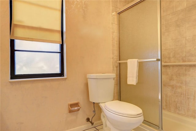 bathroom featuring toilet and a shower with door