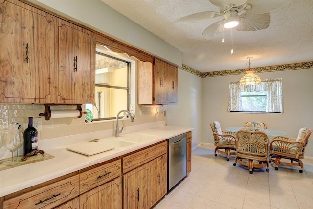 kitchen with decorative light fixtures, dishwasher, sink, backsplash, and a textured ceiling