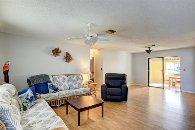 living room featuring ceiling fan, light hardwood / wood-style floors, and a textured ceiling