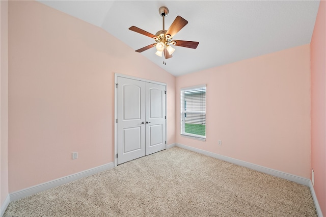 unfurnished bedroom featuring ceiling fan, a closet, vaulted ceiling, and light colored carpet