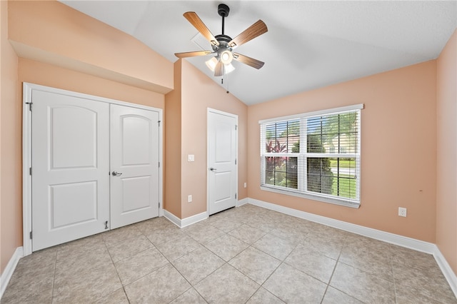 unfurnished bedroom with light tile patterned flooring, ceiling fan, a closet, and lofted ceiling