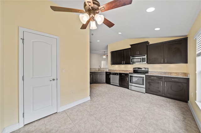 kitchen featuring stainless steel appliances, sink, light stone counters, light tile patterned floors, and vaulted ceiling