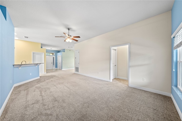 unfurnished living room with light colored carpet and ceiling fan