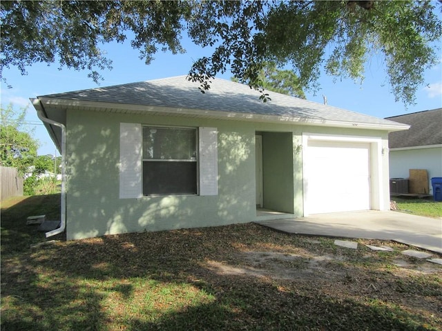 ranch-style house featuring cooling unit, driveway, roof with shingles, an attached garage, and stucco siding