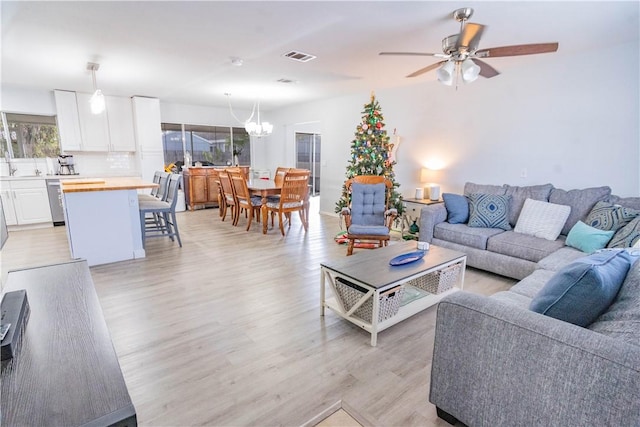 living room with light hardwood / wood-style flooring and ceiling fan with notable chandelier