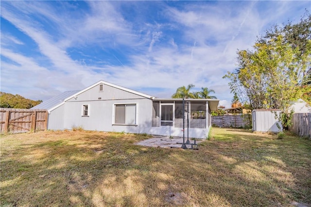 back of property featuring a lawn, a sunroom, and a storage unit