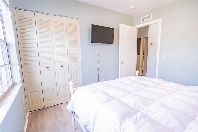 bedroom with light hardwood / wood-style floors and a closet