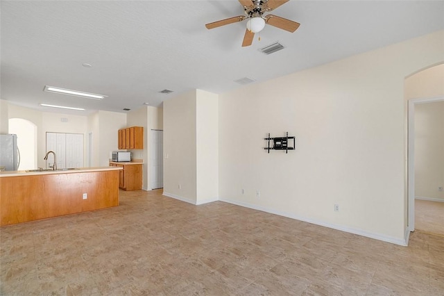 unfurnished living room featuring sink and ceiling fan