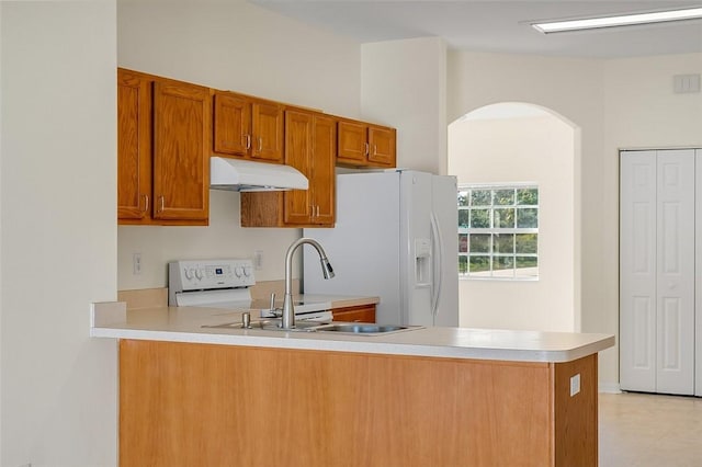 kitchen with white refrigerator with ice dispenser, kitchen peninsula, and sink