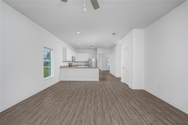 9316 104th Ave, Vero Beach, FL 32967 - unfurnished living room with dark wood-style flooring, a ceiling fan, baseboards, a textured ceiling, and recessed lighting