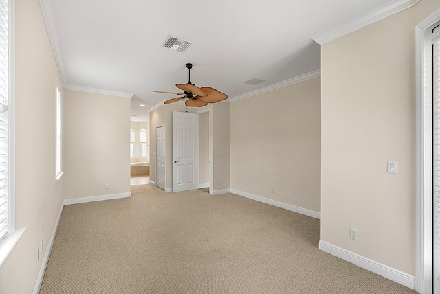 carpeted empty room with ornamental molding, a healthy amount of sunlight, and ceiling fan