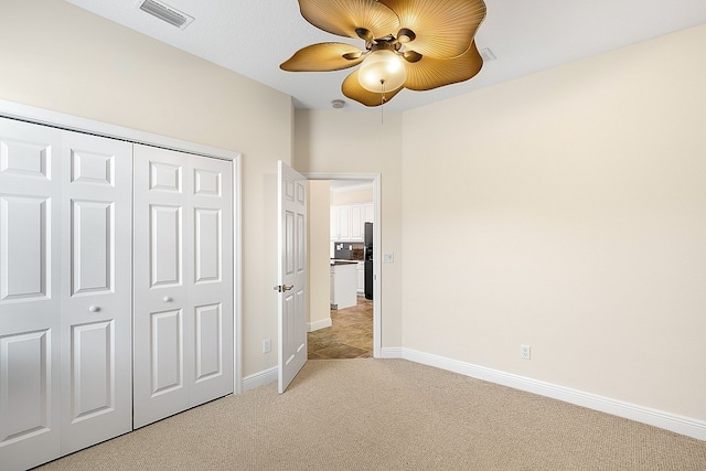 unfurnished bedroom featuring a closet, light carpet, and ceiling fan