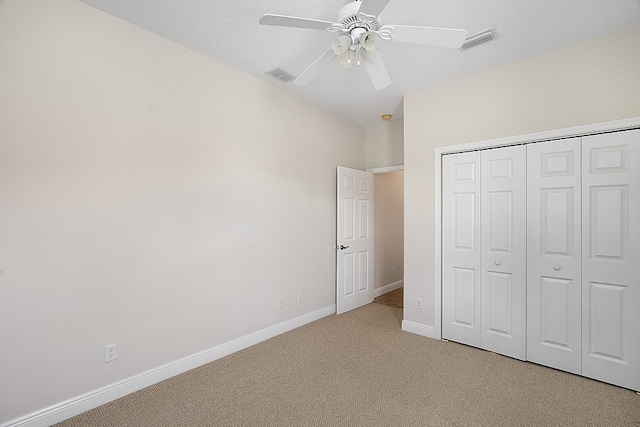 unfurnished bedroom featuring a textured ceiling, light colored carpet, ceiling fan, and a closet