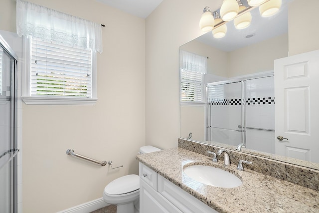 bathroom featuring vanity, a shower with shower door, plenty of natural light, and toilet