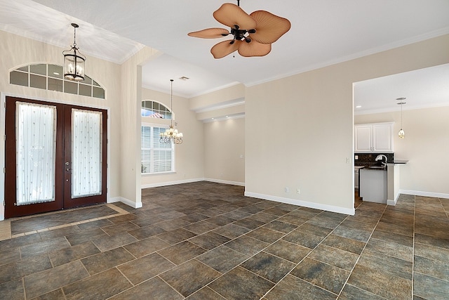 entrance foyer with ornamental molding, french doors, and ceiling fan with notable chandelier